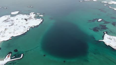 drone view in tromso area in winter flying over a snowy landscape surrounded by clear blue water in norway