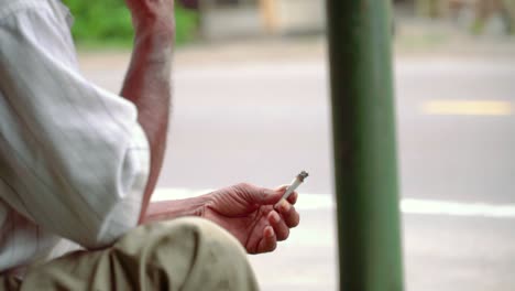 slow motion - close up shot of hand of poorman holding a cigarette on the side of road