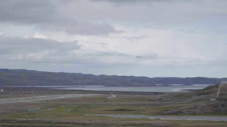 Bredt landskabsbillede af et canadisk North kommercielt passagerfly på sidste indflyvning, lavt over tundra-terrænet og bugten mod landingsbanen