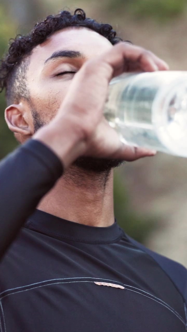 Giovane uomo che beve acqua dopo un allenamento all'aperto