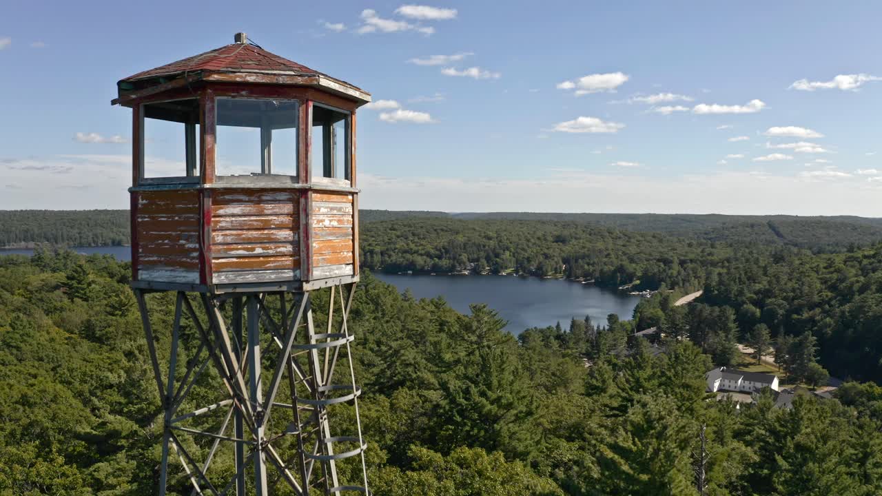 Drone rising toward lookout tower beside Ontario lake