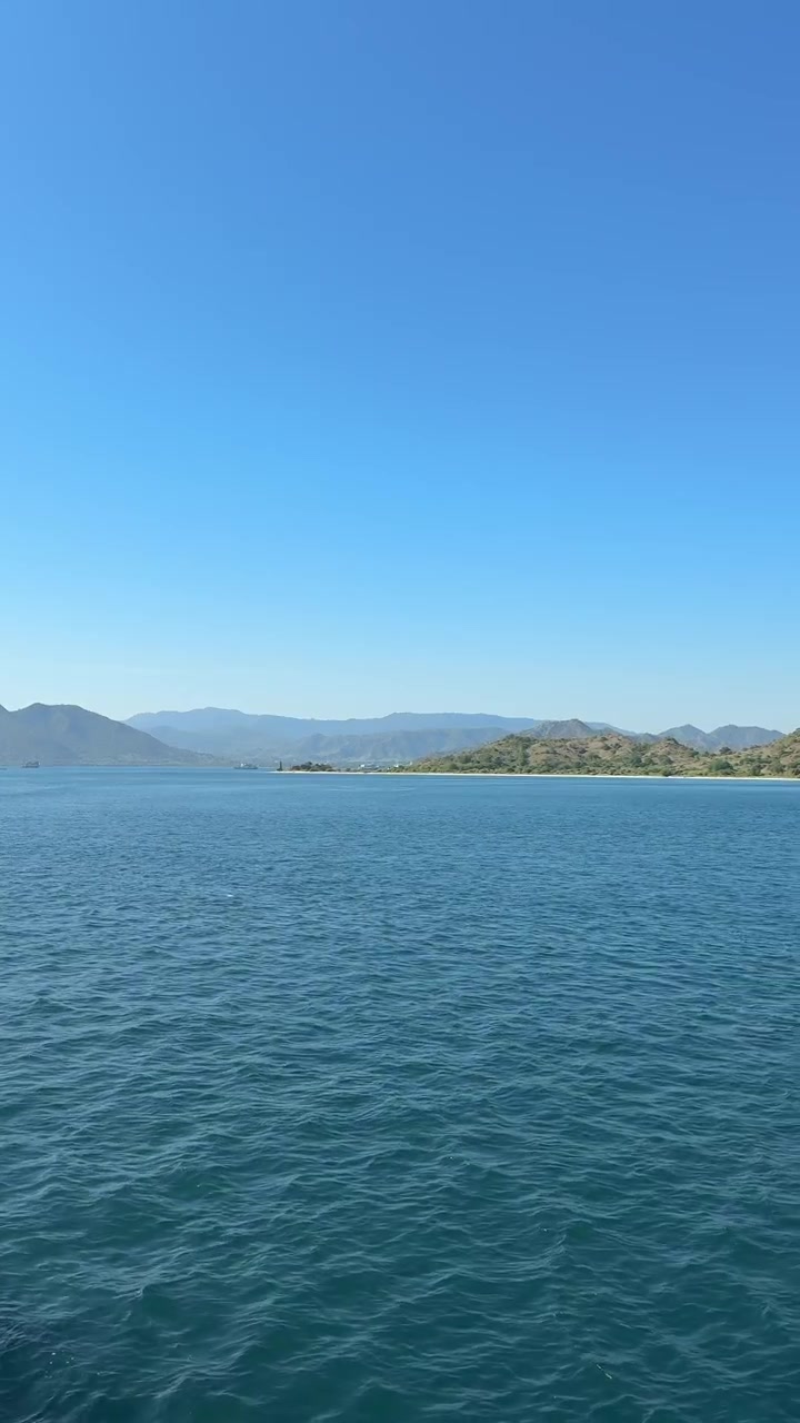 Ruhiges blaues Meer mit fernen Bergen unter klarem Himmel