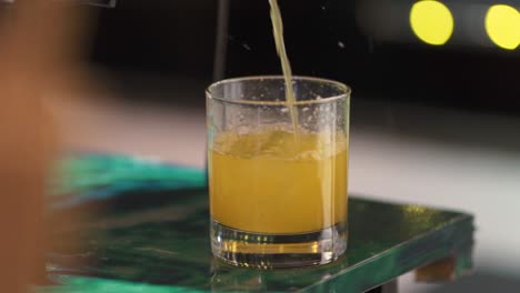 orange drink poured into a glass at wedding party bar