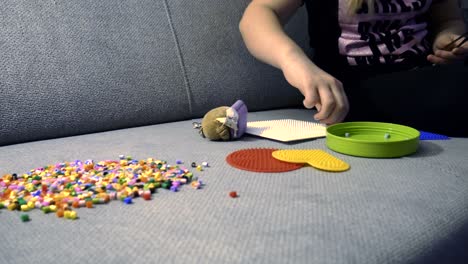 child making art with perler beads,on the sofa