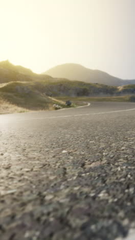 empty winding road through mountains at sunset