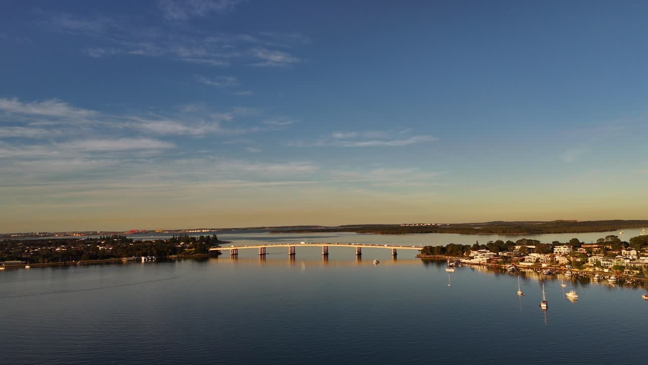 Drone approach low to Captain Cook Bridge spanning Georges River under blue skies, Sydney NSW Australia