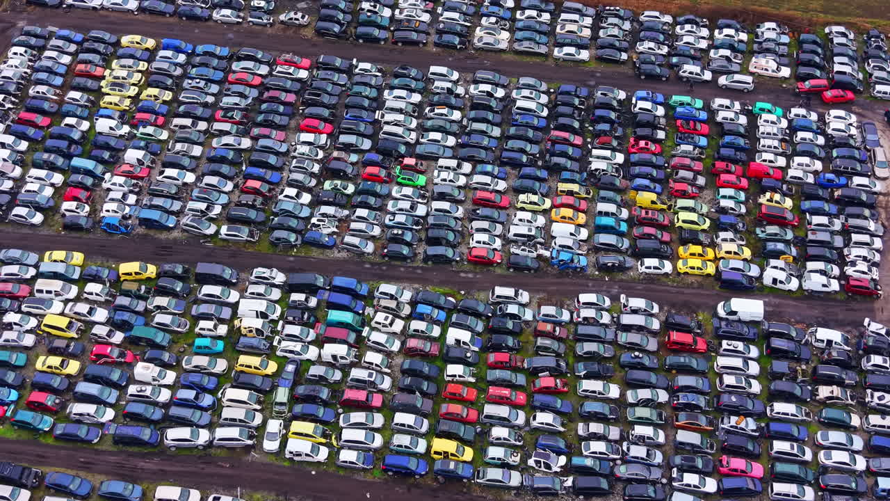 Stor samling af parkerede biler på en losseplads i fuldt dagslys med mange farver og forskellige modeller synlige