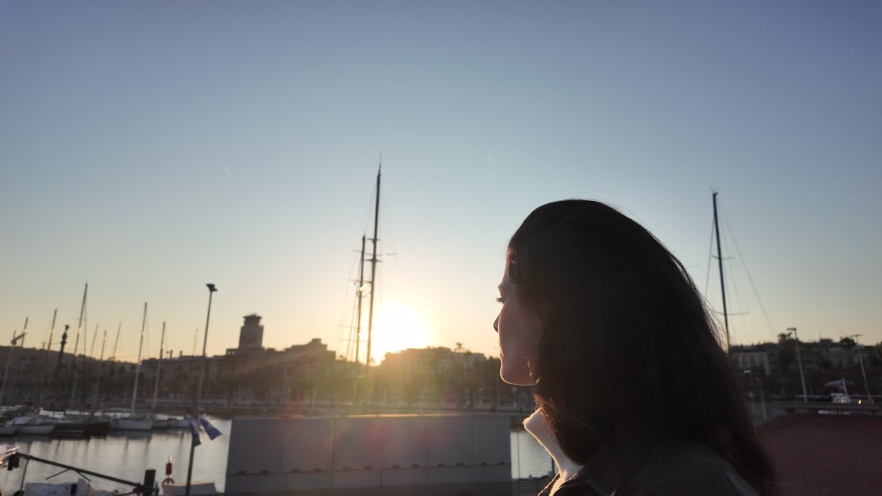 Woman silhouette backlit by sunset marina with sailboat masts