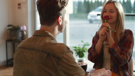 young man giving rose to woman in cafe 4k