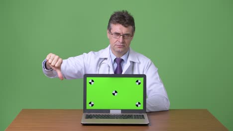 hombre maduro y guapo médico contra fondo verde