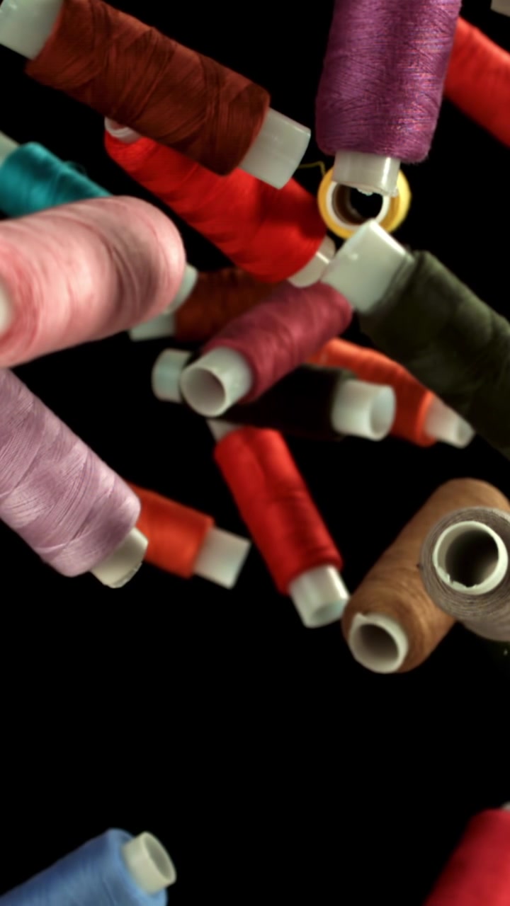 Colorful Spools of Thread Falling in Slow Motion on Black Background