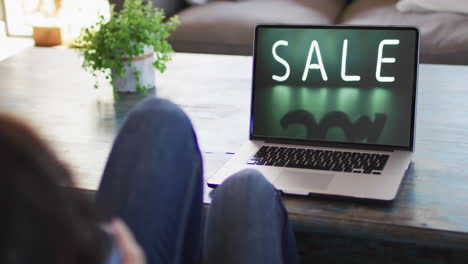 Knees-of-woman-at-table-using-laptop,-online-shopping-during-sale,-slow-motion