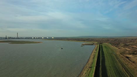 aerial : coastal green bank with industrial tankers refinery in view