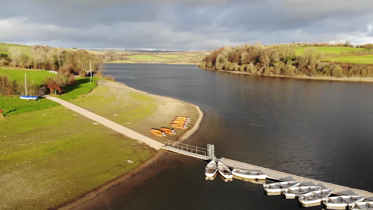 Aerial forward shot of moored boats at the side of Wimbleball Lake Exmoor England at sunset