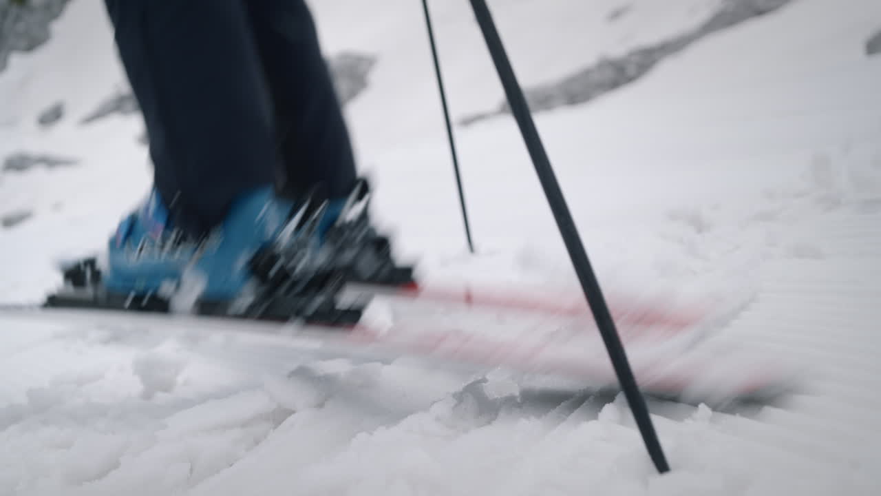 Close camera shot of a woman standing on snow with skis and ski boots, she turns the skis and starts to ski downhill