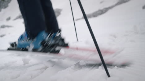 close camera shot of a woman standing on snow with skis and ski boots, she turns the skis and starts to ski downhill