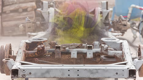 Close-up-shot-of-man-in-a-protective-clothing-and-hard-hat-processes-metal-with-a-stream-of-sand