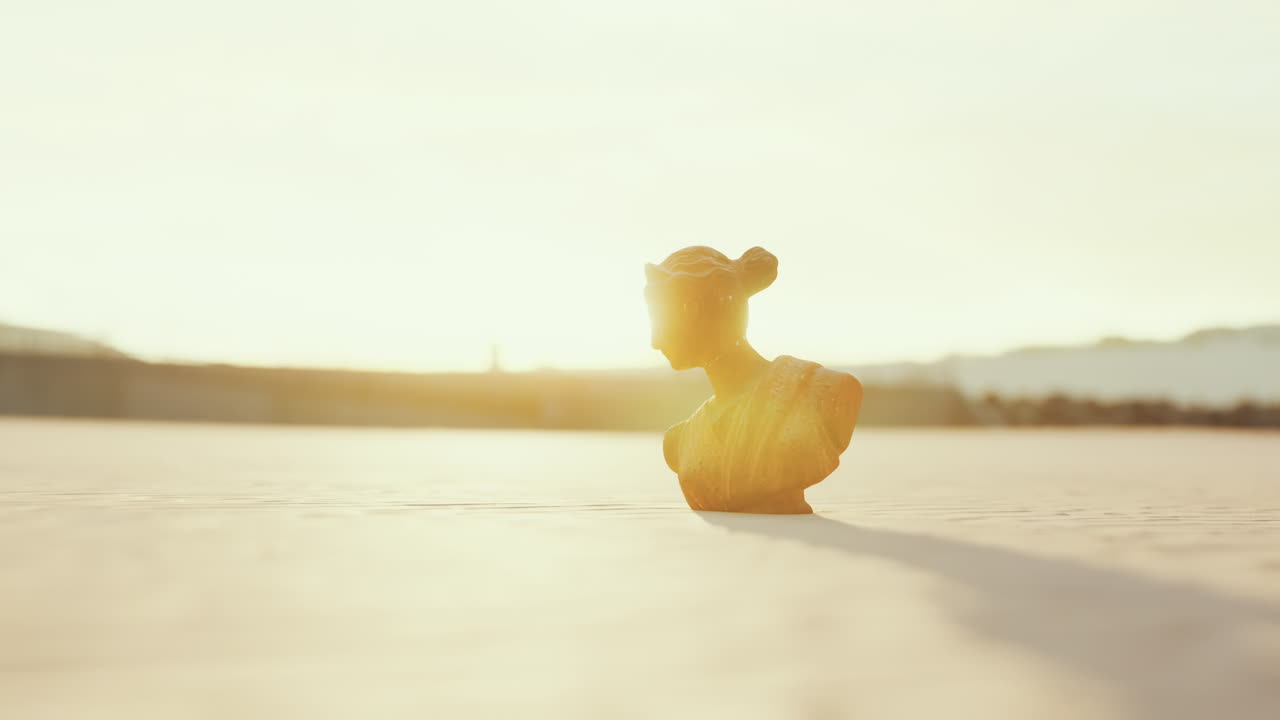 해가 지는 동안 사막에 있는 고대 동상