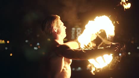 Young-blond-male-spins-two-burning-pois-ties-them-together-Slow-motion-shot-Close-up-shot