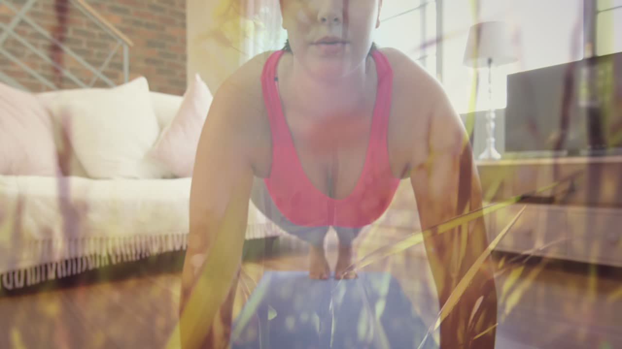 잔디는 바람에 따라 움직이고 백인 여성은 집에서 판자 운동을 수행합니다.