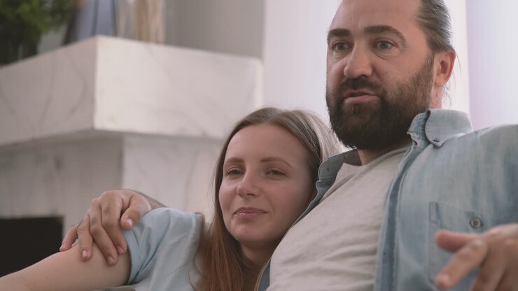 Uomo barbuto conversa con la sua partner, una donna attraente, che appoggia la testa sulla sua spalla 1