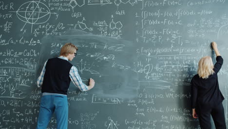 two adults writing equations on a chalkboard