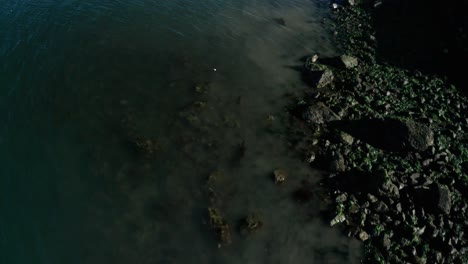 A-green-blue-shoreline-of-rocks-and-bay-water