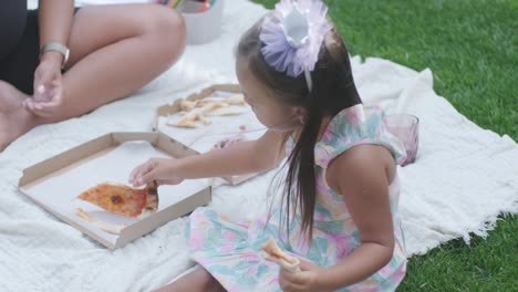 a mother and her young daughter sit on a blanket in the backyard, engaging in a drawing activity together. the outdoor scene captures a peaceful family moment, fostering creativity and bonding.