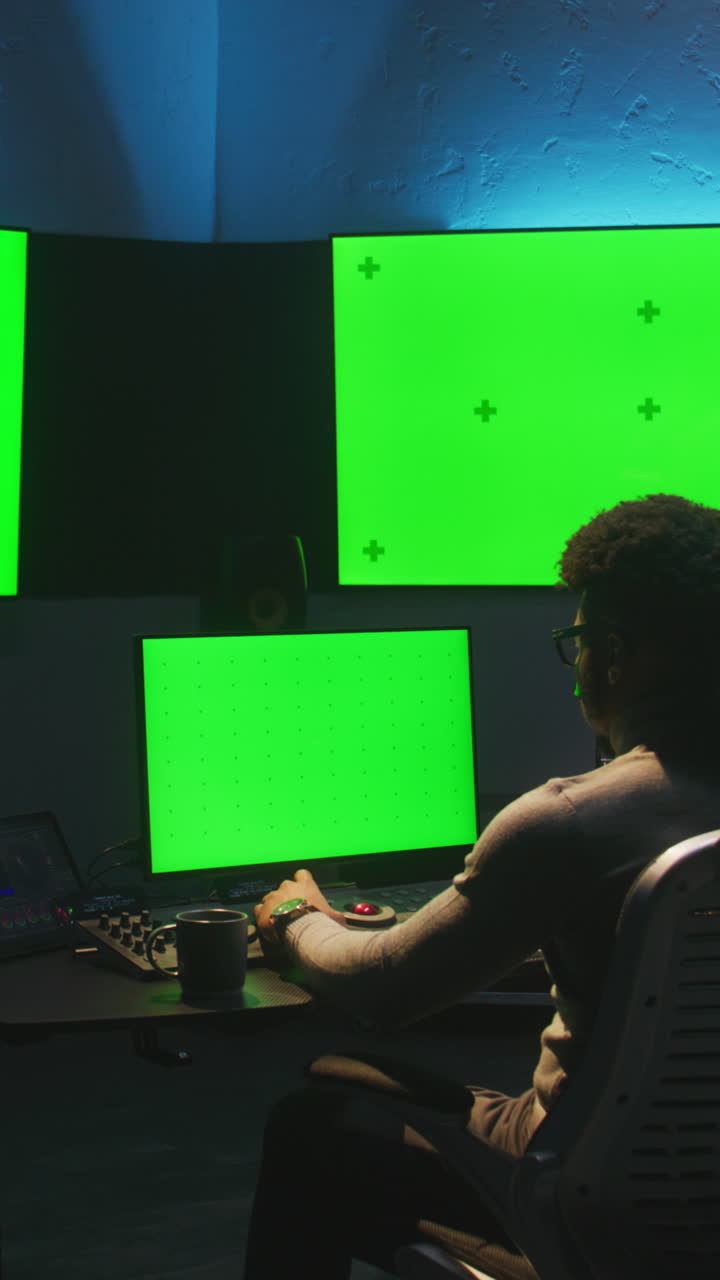Video Editor at Work in a Modern Editing Suite with Green Screens