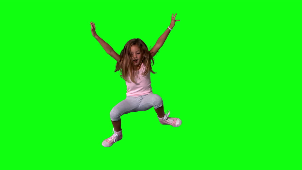 Carina bambina che salta con gli arti distesi su schermo verde
