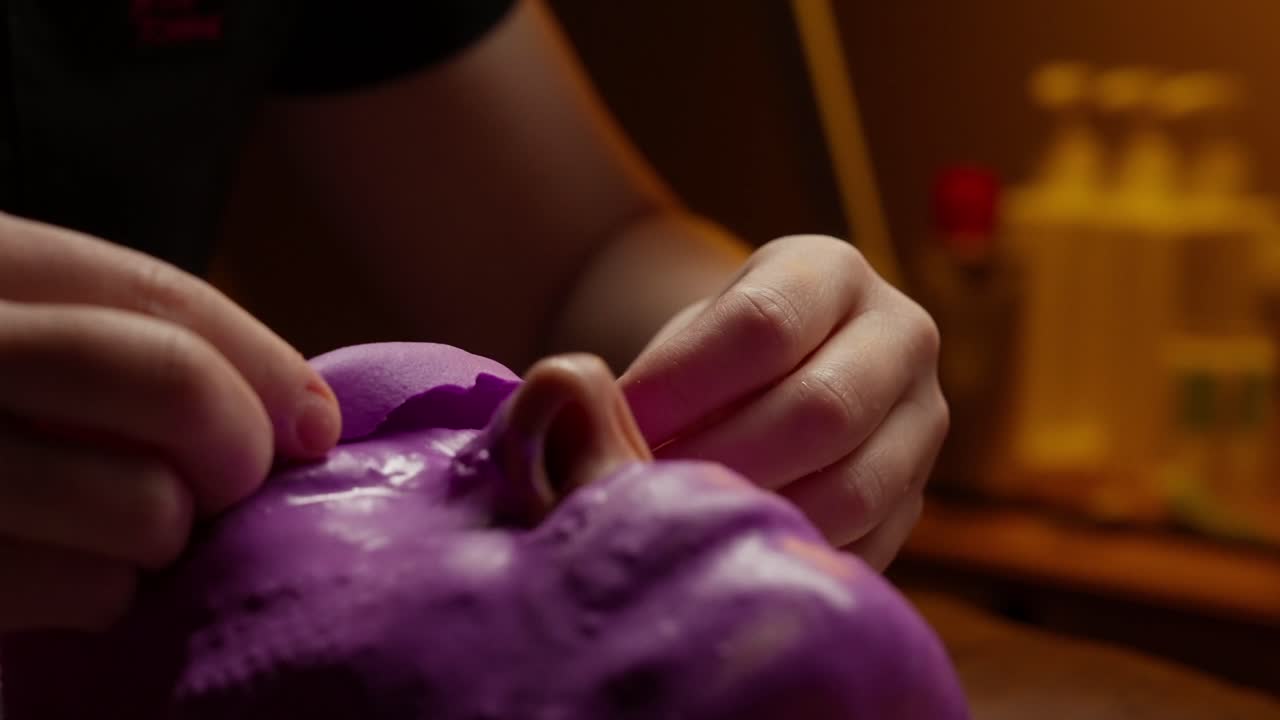 Manos aplicando suavemente una mascarilla facial morada en el rostro de una persona