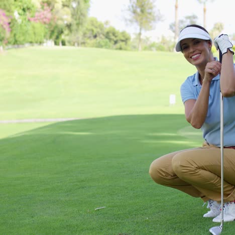 Lächelnde-Golferin-Mit-Braunen-Haaren-Hockt