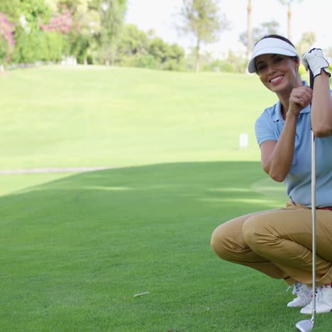 una golfista sonriente con cabello castaño se agacha