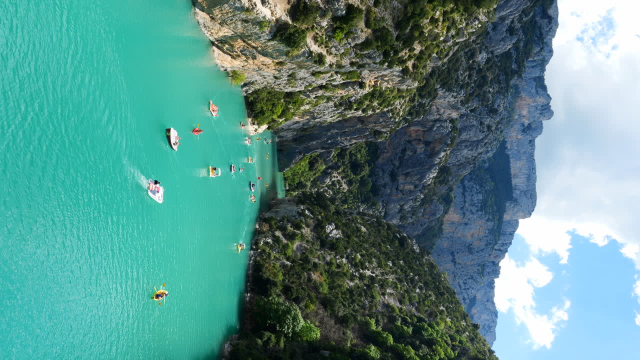 Boats and kayaks on a turquoise river in a scenic gorge with steep cliffs