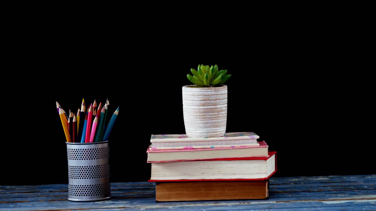 Pot plant on book stack with pencil color on table