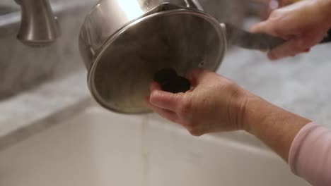 woman straining pasta water in sink in slow motion