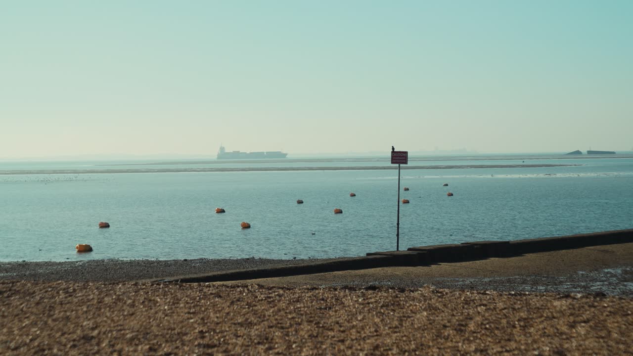 A wide slow mo, tranquil shot of small fishing boats moored in shallow water at low tide along the English coast in Southend-on-Sea, United Kingdom. Calm blue sea, peaceful coastal seascape