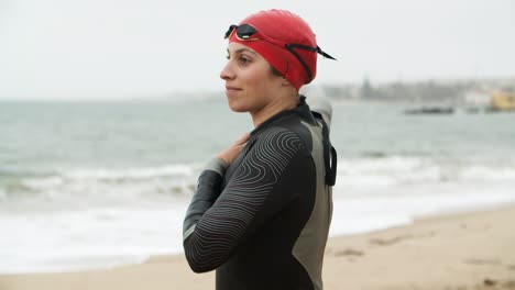 female swimmer stretching on beach