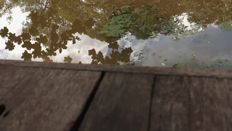 Toma-Deslizante-De-Reflejos-En-El-Río-Visto-Desde-Un-Embarcadero-De-Madera