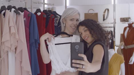 happy female friends enjoying shopping together and making selfie photos