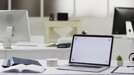 Laptop-computer-with-illuminated-screen-on-desk-in-empty-office