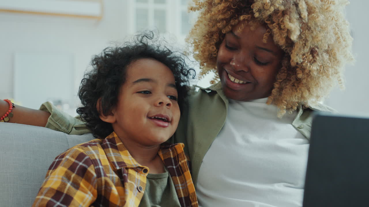 Cheerful Mother and Son Watching Cartoon on Laptop and Laughing at Home