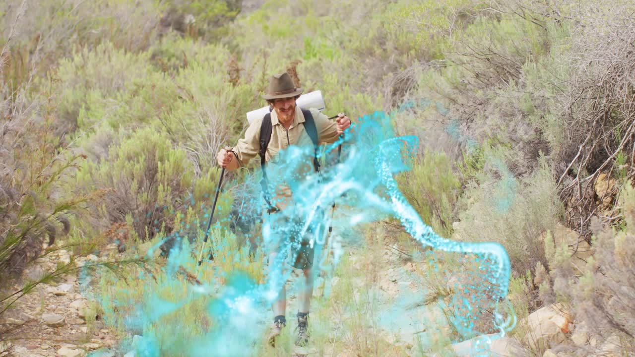 Senderista masculino subiendo por un sendero estrecho, provocando una ola turquesa que barre alrededor de los postes, sonriendo por la caminata.