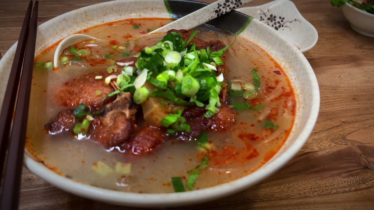 Slow dolly in crane shot of a bowl of Chinese pork noodles on a table