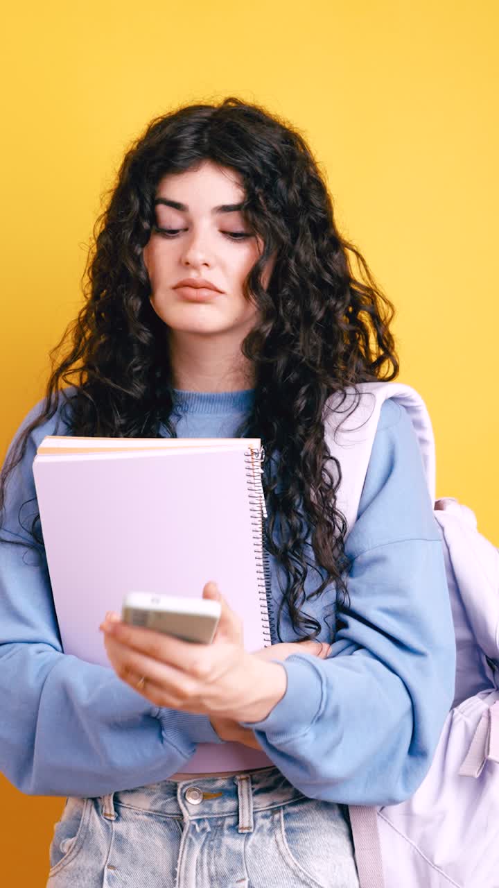 Ritratto di una giovane donna con i capelli ricci che tiene in mano un quaderno e un telefono