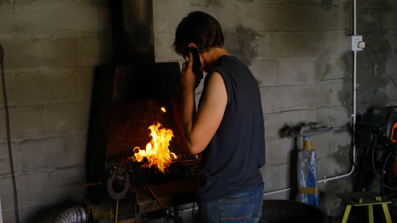 metalúrgico hablando por teléfono móvil mientras trabajaba en la fábrica 4k