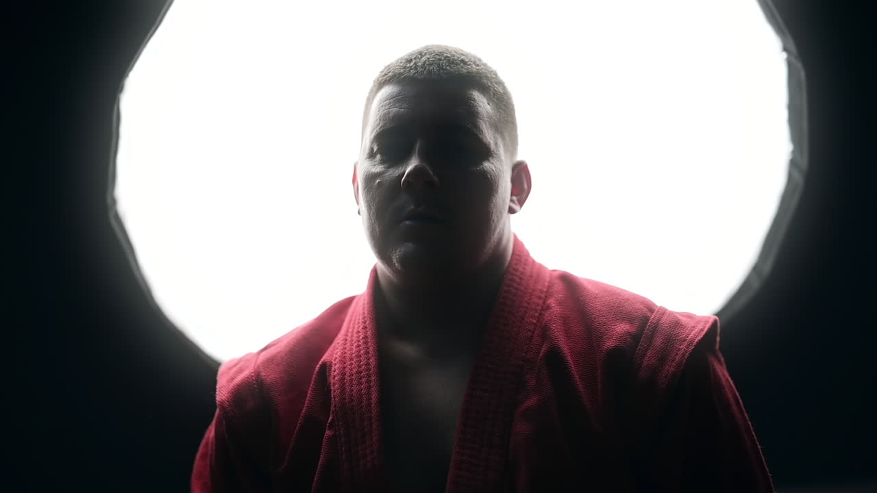 Taekwondo practitioner in a red kimono is boxing in front of him in a gym. Slow motion