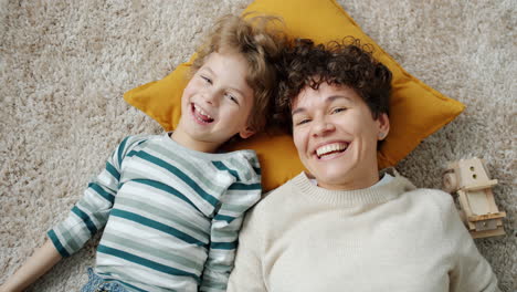 happy mother and son laying on carpet