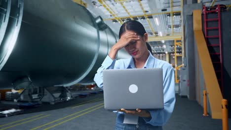 asian woman not satisfied and shakes her head while using laptop computer in pipe manufacturing factory