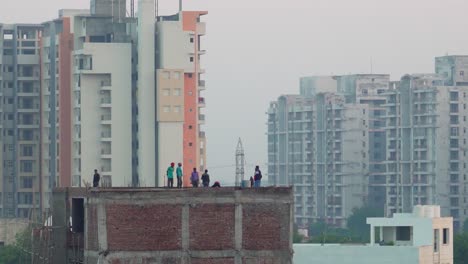 group of people standing on the roof of house with high skyscraper in distance, city during golden blue hour sunset
